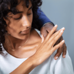 What is quid pro quo? A businessman has his hand on a female coworker's shoulder and she is pushing it away.
